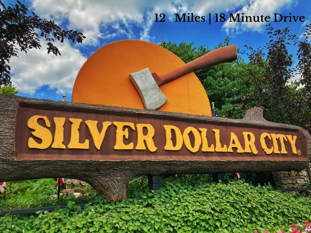 A vibrant exterior shot featuring the iconic 'SILVER DOLLAR CITY' sign with a giant axe and a bright orange backdrop. The image conveys the excitement and charm of visiting one of Branson's most famous attractions.