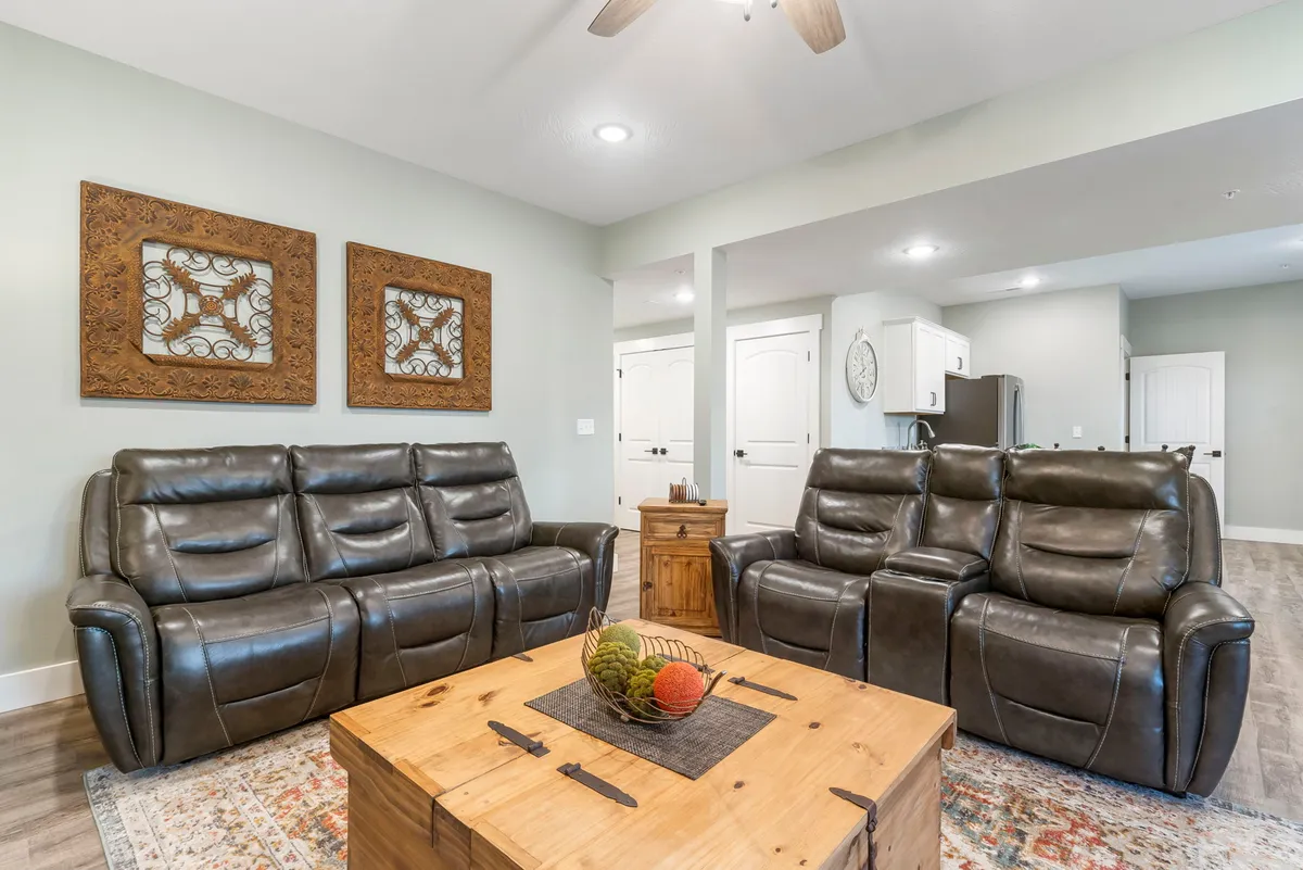 A cozy lower-level living space featuring leather recliners, a coffee table, and decorative wall art. The arrangement invites relaxation, conversation, and group gatherings for game nights or family time.