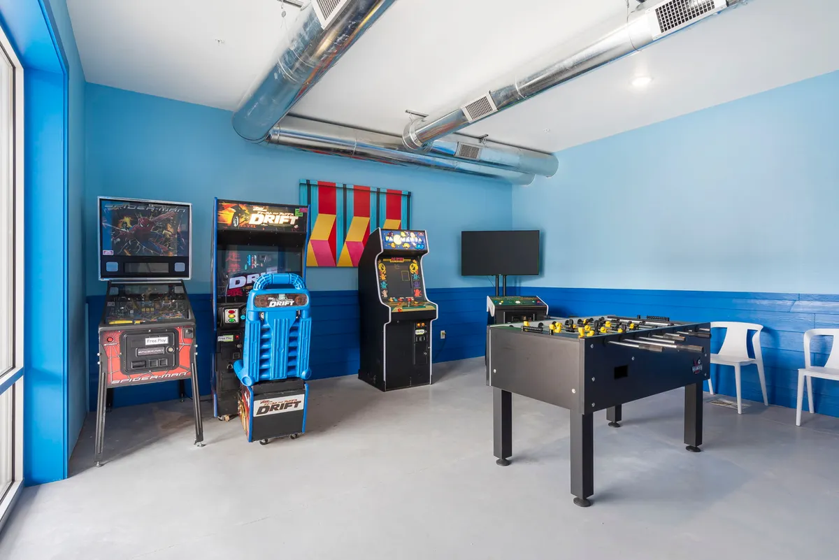 A vibrant interior image of an arcade filled with modern arcade machines, a foosball table, and colorful decor. The room is designed for high-energy fun and friendly competition, appealing to both children and adults alike.