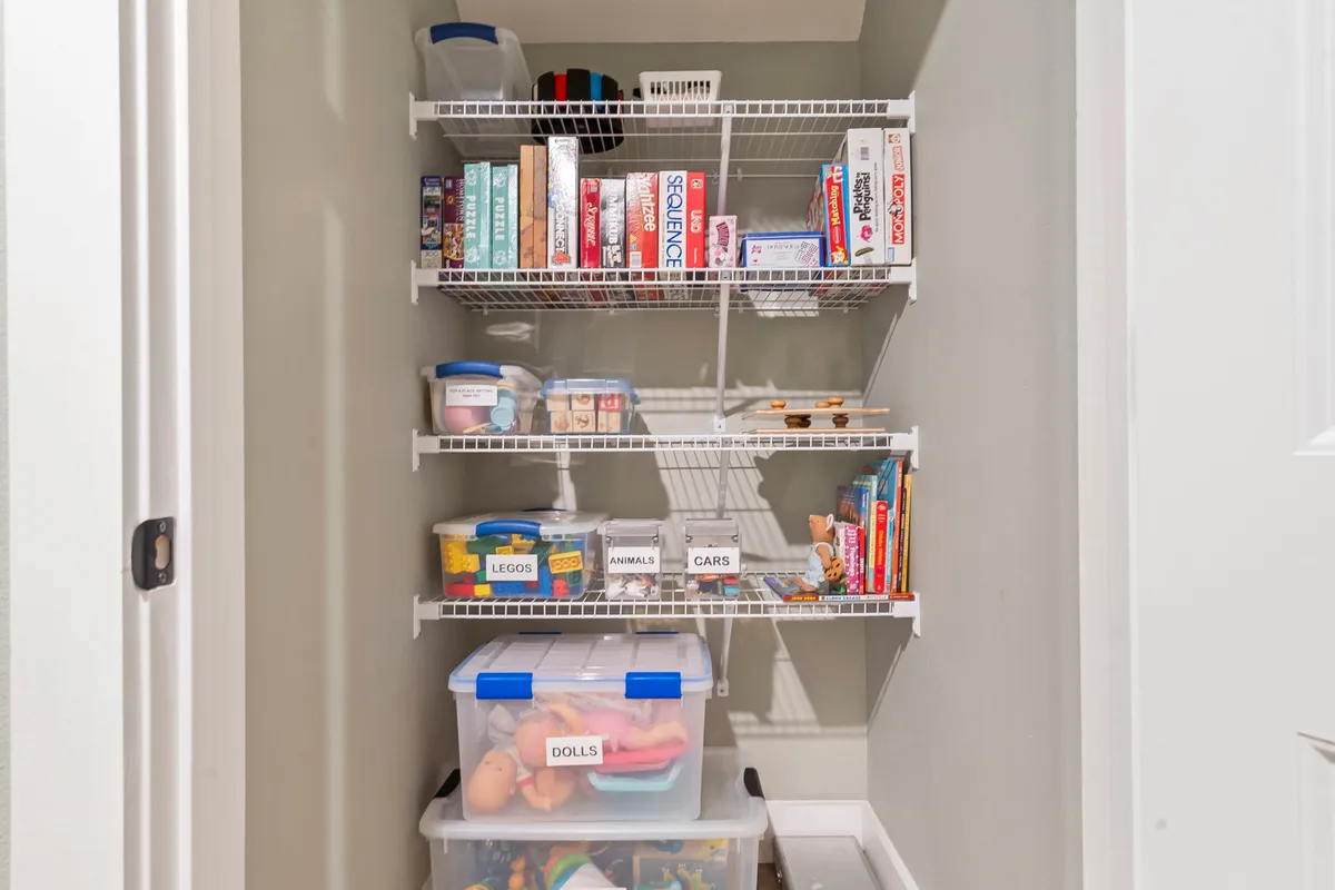 Shelves packed with a variety of board games and toys, with labeled storage bins and a cheerful, organized play area. The space feels inviting and ready for family fun, reflecting a dedicated children's zone perfect for imaginative play and group activities.